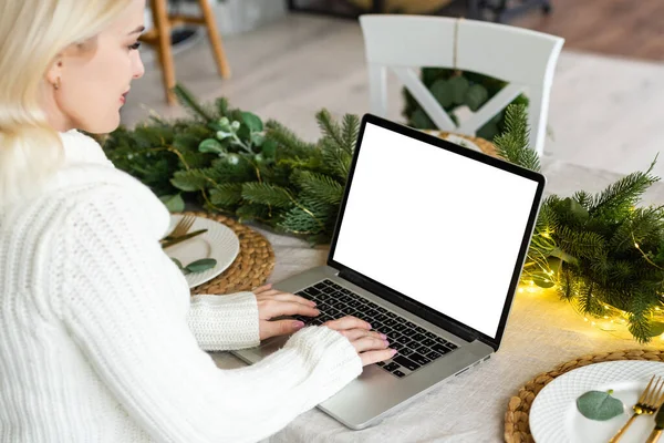 Young woman work on laptop with blank display screen with mockup copy space. Modern home living room interior design. Work at home concept. christmas.