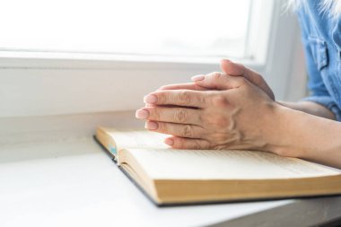 İnanç, maneviyat ve din için kutsal bir İncil üzerine dua ederken, sabahları kutsal İncil 'e dua eden bir kadın. İncil 'e dua eden kadın eli