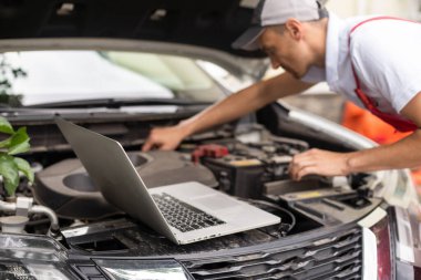 Makinist araba motoru yakınındaki dizüstü bilgisayar ile. Modern araba tanılama programı üstünde perde. Araba hizmet anlayışı.