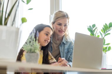 Güzel anne ve çocuk dizüstü bilgisayar ekranında app eğitim programı kullanarak mutfakta zaman geçirmek bakar, karikatürler seçin, çocuk pc kullanımını öğretmek, internet siber uzay konsepti ne kızı izlerken kontrol