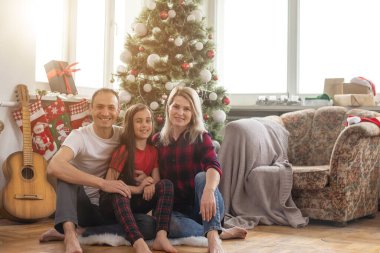 Mutlu Noeller ve mutlu yıllar. Mutlu aile evde güzel bir Noel ağacının yanında otururken yeni yılı bekliyor..
