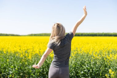 young woman posing in beautiful yellow blooming rapeseed or oilseed rape field. girl holding bubble blower and making big bubbles. lady having fun. spring nature wallpaper. farming.