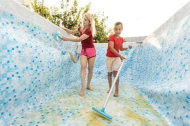 Anne ve kızı bahçede yüzme havuzu temizliyor..