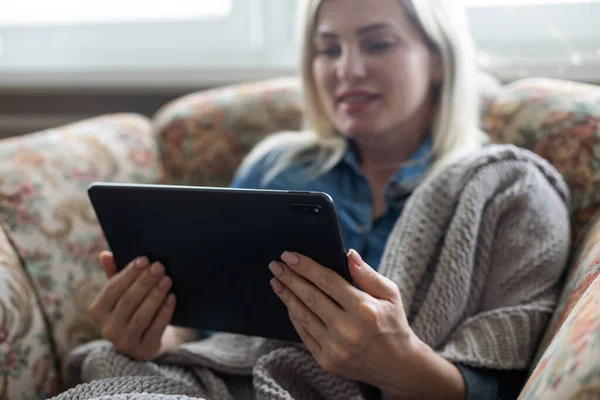 Happy young woman with tablet pc laying on sofa