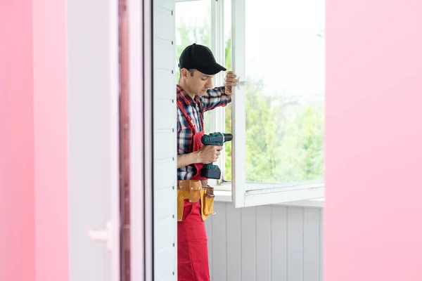 Construction worker repairing plastic window with screwdriver indoors, closeup