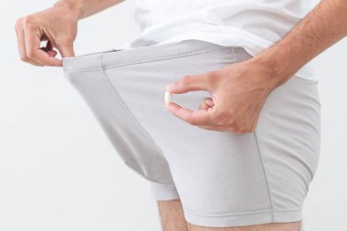 İç çamaşırlı bir adam hap tutuyor..