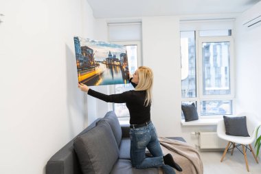 Çekici, mutlu, genç bir kadın elinde bir tuval tutuyor.