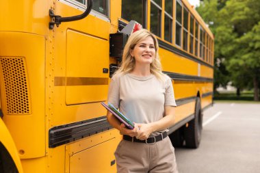 Teacher of elementary school near the school bus.