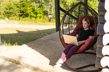 Evden çalışmak ya da internetten çalışmak. Terasta dizüstü bilgisayarda çalışan bir kadınla çalışmak..