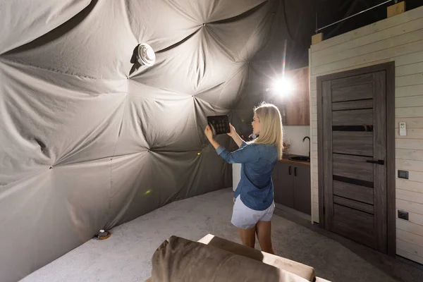 woman with tablet turning on ventilation system as a recuperator for fresh indoor air quality, smart home.