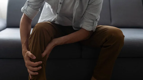 Young Man Who Has Hurt His Knee Sitting Sofa Hugging — Stock Fotó