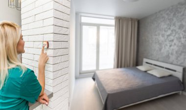 Woman controlling smart home devices using a digital tablet with launched application in the white living room. Smart home concept. High quality photo