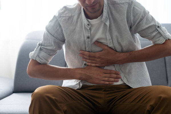 Young handsome man having stomach ache.