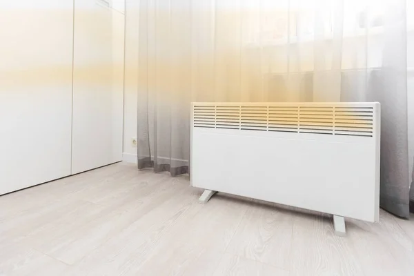 Modern electric heater on floor at home. Space for text.
