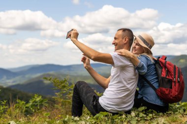 Sırt çantalı yürüyüşçüler dağın tepesinde dinleniyor ve manzaranın tadını çıkarıyorlar..