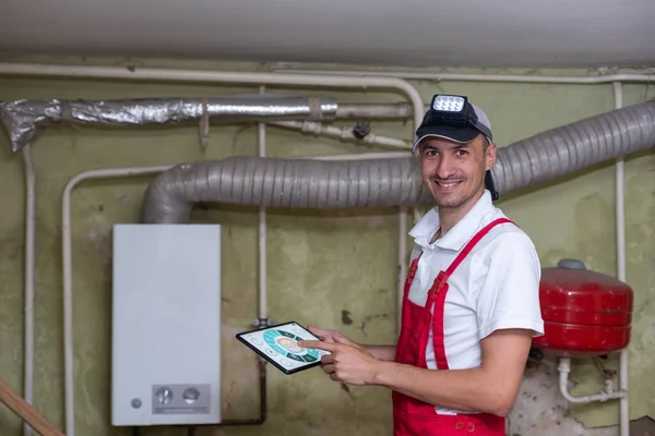 The technician checking the heating system in the boiler room with tablet in hand