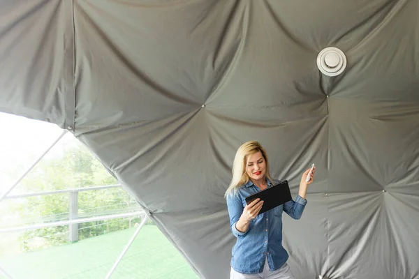 woman with tablet turning on ventilation system as a recuperator for fresh indoor air quality, smart home.