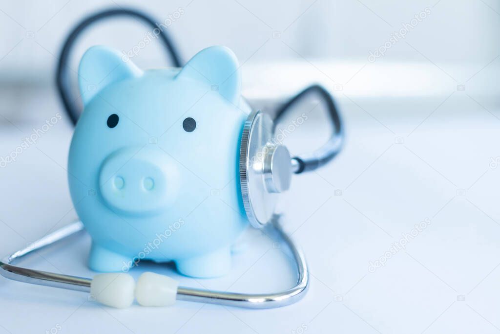 Piggy bank with stethoscope isolated on light blue background with copy space. Health care financial checkup or saving for medical insurance costs concept.