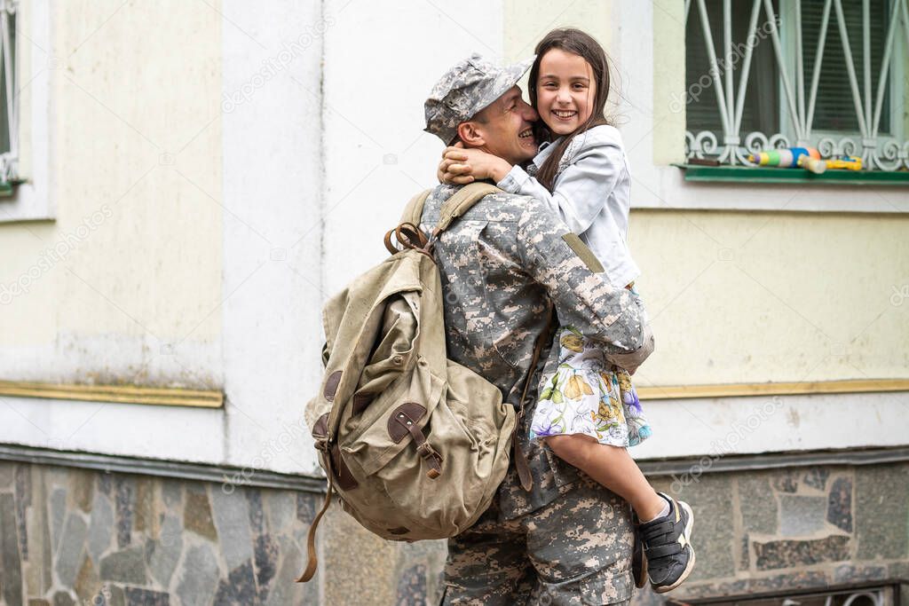 Little child is very happy her father came back from army. Little kid is hugging her father.
