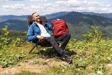 Dağlarda sandalyede oturan bir adam.