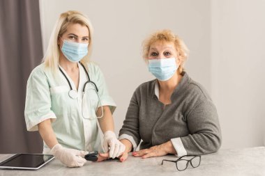 Doktor yaşlı kadın hastayla hastalık belirtileri hakkında konuştu, doktor yaşlı hastayla parmak ucu nabız oksimetresi, yaşlı sağlık kontrolü ve sağlık taraması, tıbbi teknoloji kullandı..