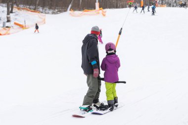Kayak merkezinin babası Küçük Kızına Snowboard öğretiyor.