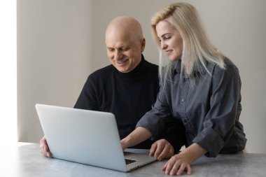 Ön manzara mutlu 70 'li yaşlılar gri saçlı adam bilgisayar yazılımı kullanarak yetişkin kız, emekli yaşlı insanlar ve modern teknoloji kavramını öğreniyor..