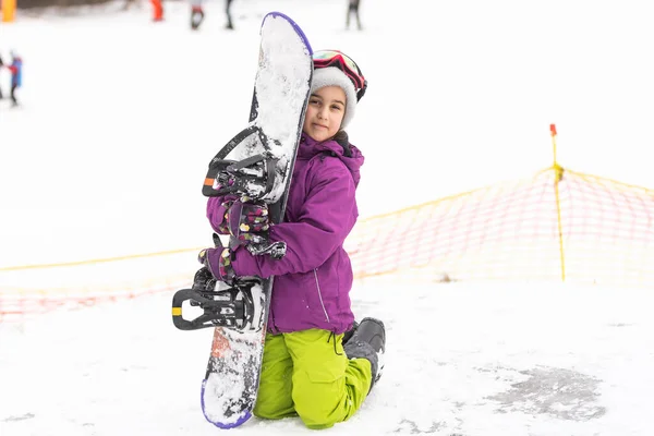 Snowboard winter sport. Cute girl with snowboard going to slide in winter nature.