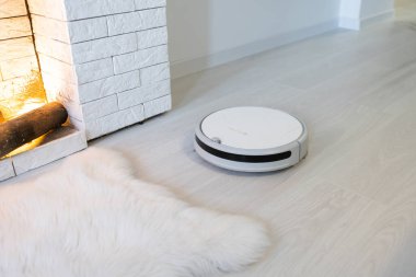 Kablosuz robot süpürge oturma odasındaki ahşap zemini temizliyor..