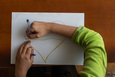 Bir kalp çizen çocuğun ellerine yakın çekim.