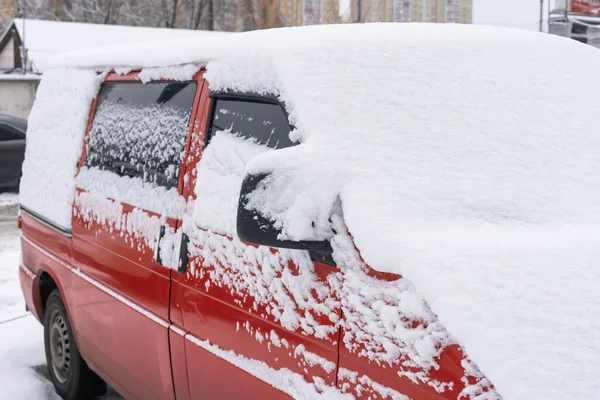 Donmuş araba kış günü karla kaplı, ön cam ön cam manzaralı ve karlı arka planda kaput.