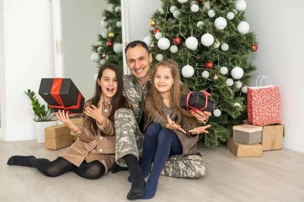 Soldier returning home to join his family for Christmas vacations. military father and family near christmas tree.