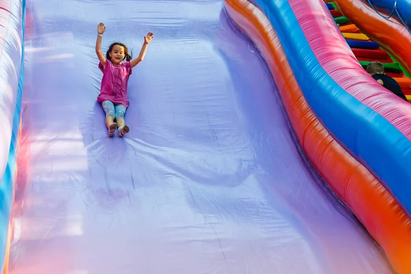 スライド中にジャンプ城で多くの楽しみを持っている幸せな女の子 — ストック写真