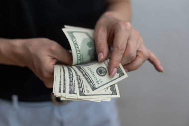 Beyaz duvar arkasında para tutan genç bir kız.