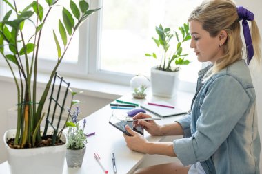 Ofisinde dijital tablet kullanan genç bir iş kadını.