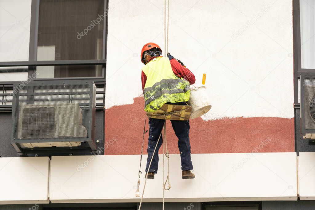 construction worker is painting a wall with a roller.