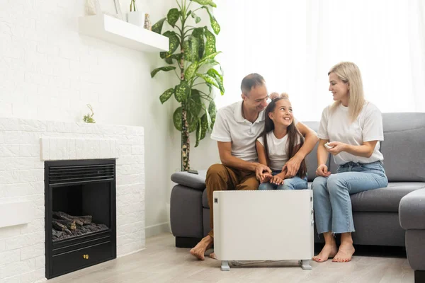 Family warming up near home heater at winter cold time. The symbolic image of the heating season at home