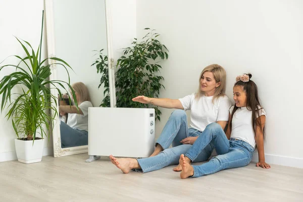 Family warming near electric heater at home