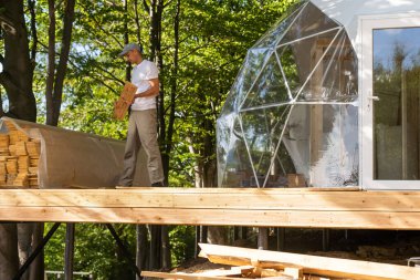 the master builds the dome. Outside spherical glamping dome. Hemispherical structure lattice shell geodesic polyhedron. Camping house hotel party tent