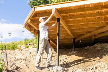Evin yanına ahşap malzemeler yapıyor. Ahşap ev inşa etme süreci. Çerçeve inşaatı. İnşaat alanında kereste. Konsept: İnşaat için kereste satışı. Kereste satışı.