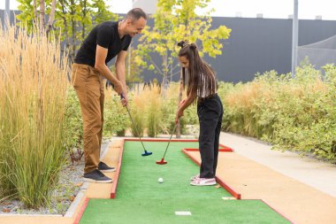 father and daughter playing mini golf.