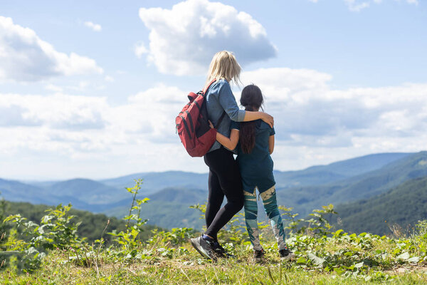 Mother and child with a backpack enjoying in the mountains.The concept of family travel, adventure, and tourism. Lifestyle and hiking autumn vacations outdoor. Back view