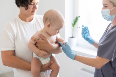 Doktor beyaz arka planda bebek aşısı yapıyor.