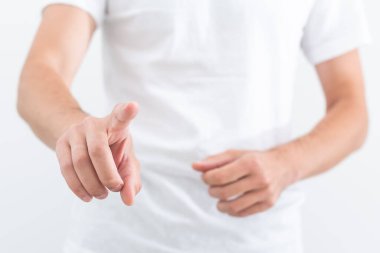 Young man in white shirt pointing up with his finger feeling excited with open mouth, showing benefit of commercial offer, isolated on gray background.