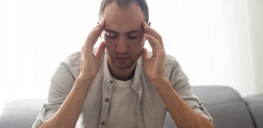 Exhausted Caucasian millennial male worker take off glasses massage eyes suffer from headache or migraine, tired man feel fatigue overwhelmed with computer work having blurry vision or sight problem