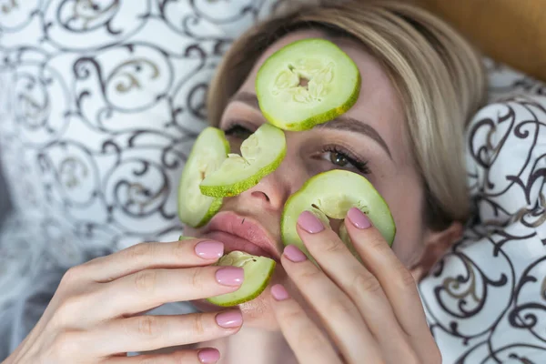 a woman with a cucumber on her face.