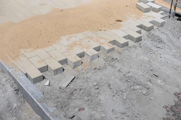 Stone blocks laying is on sand base. Sidewalk device