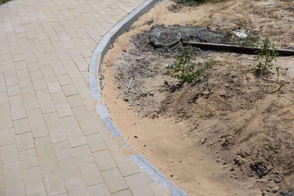 Stone blocks laying is on sand base. Sidewalk device