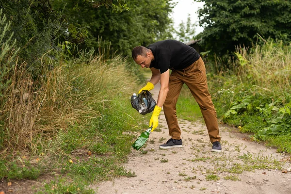 young man picking up trash outdoor. close up.