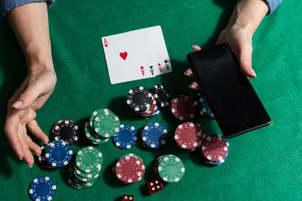 カードやチップ付きのカジノテーブルでスマートフォンを持つオンラインポーカープレーヤー — ストック写真